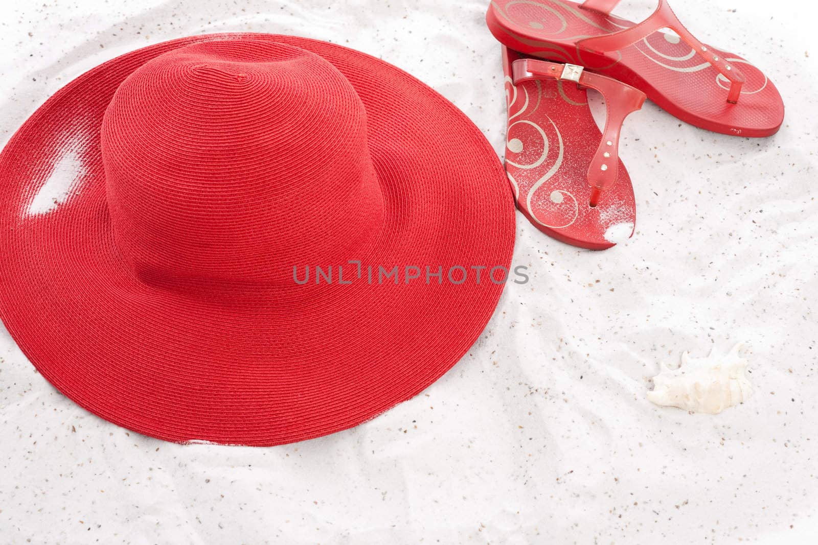 Big summerhat and flipflops lying in the sand