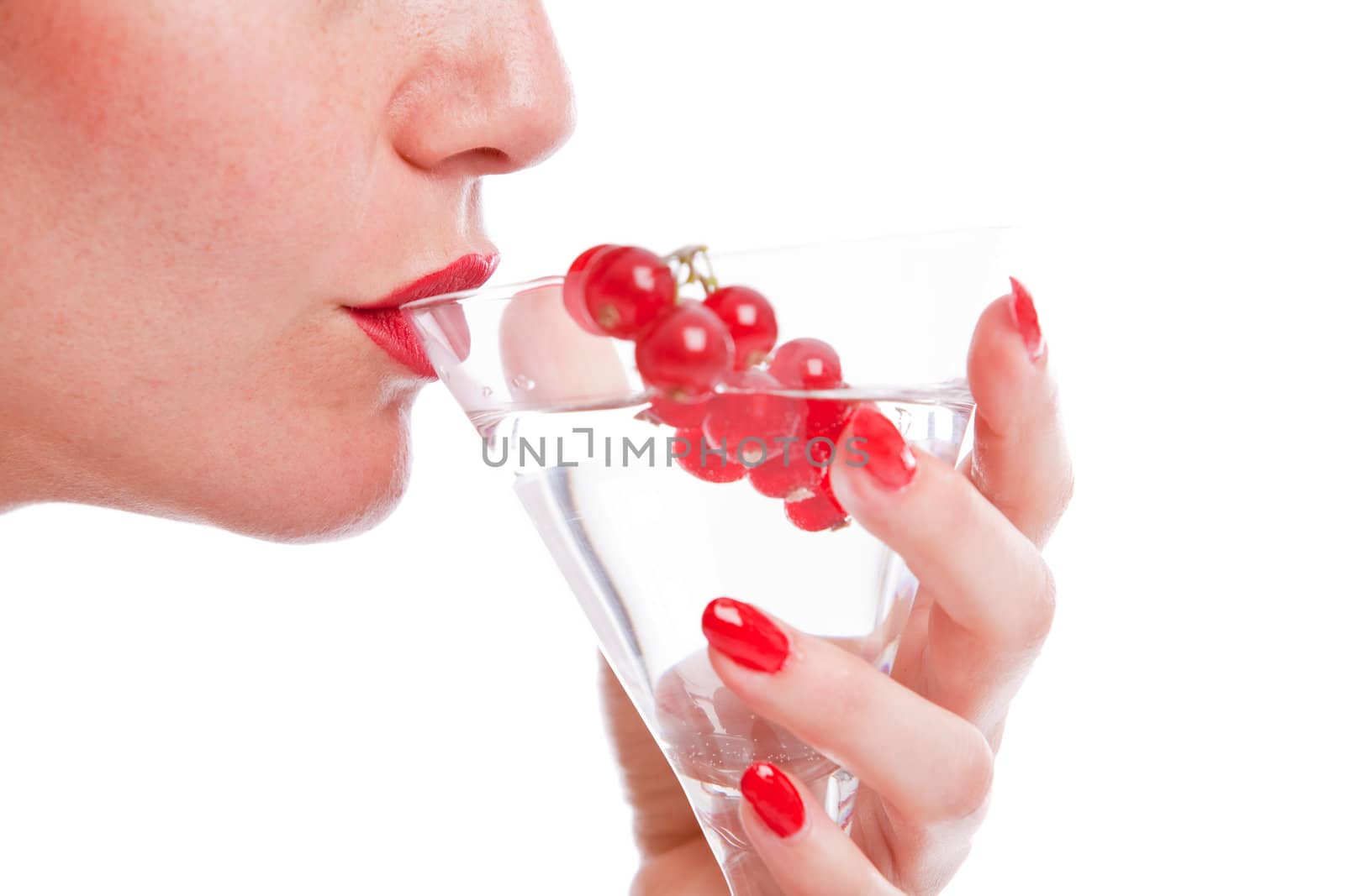Woman mouth drinking from a cocktail glass decorated with red berries