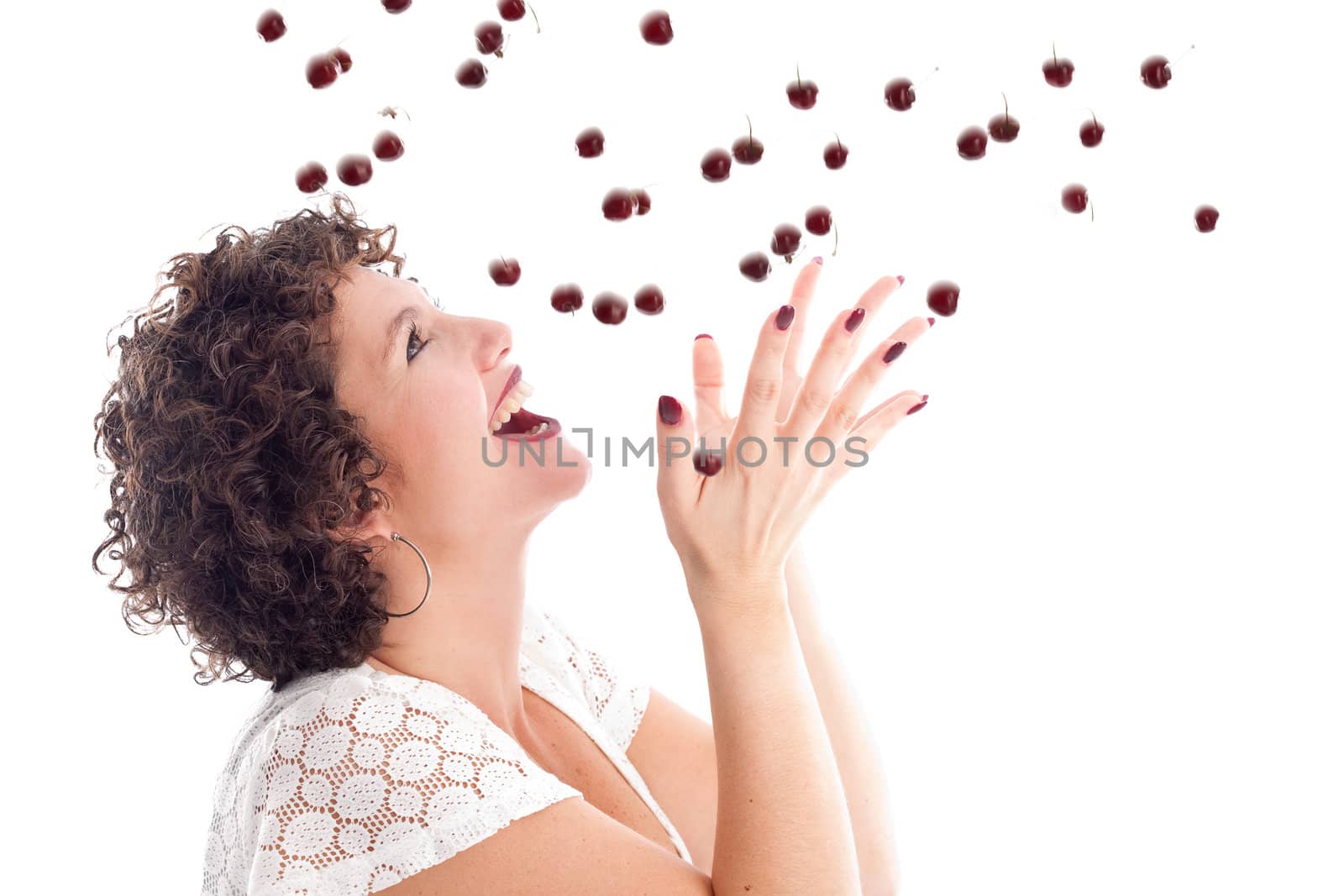 Pretty brunette with curls catching a drop of cherries
