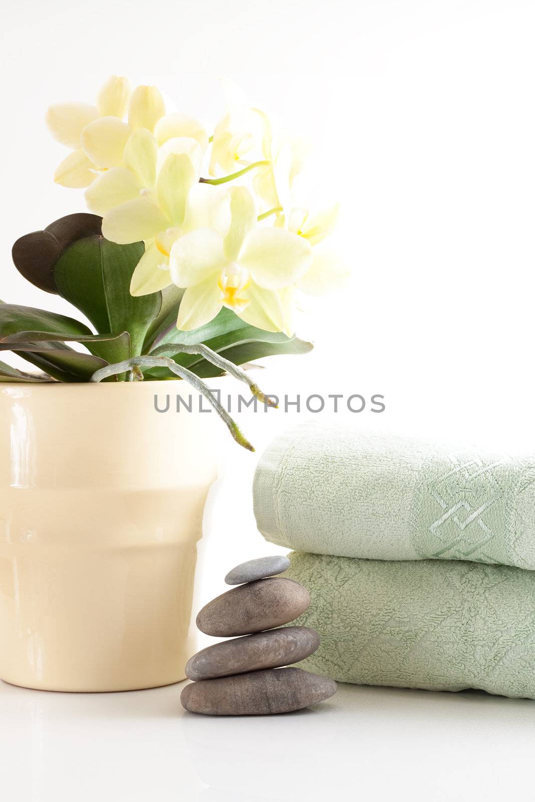 Yellow orchid, massage stones, two towels isolated on white background