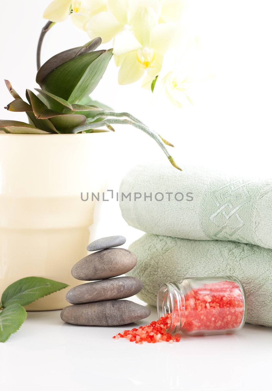 Yellow orchid, massage stones, bath salt and two towels isolated on white background