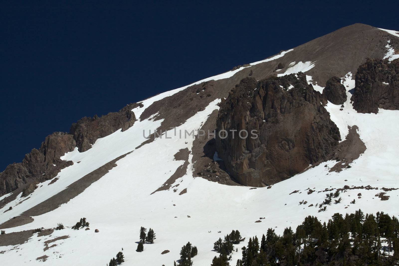 Granite mountain peak  with snow against deep blue sky