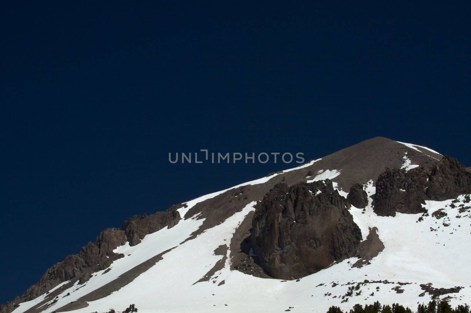 Granite mountain peak  with snow against deep blue sky