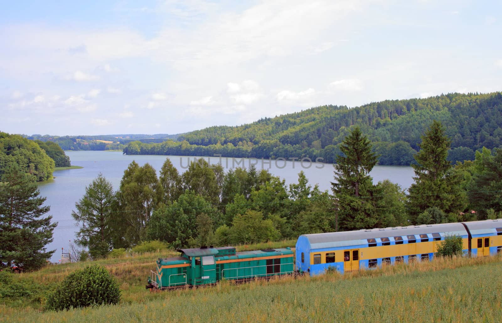 Passenger train passing the village with the river in background
