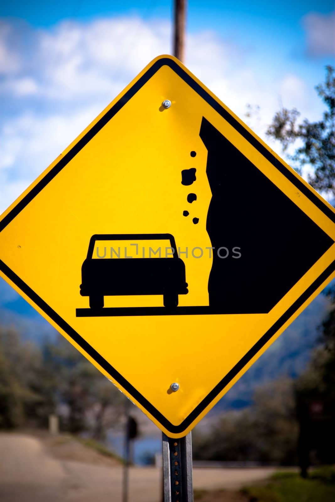 Close-up of a yellow sign with a car silhouette and falling rocks