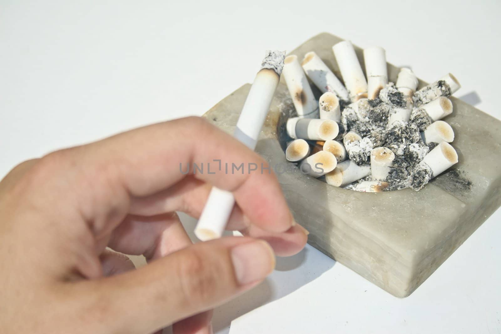 Full ashtray and hand holding cigarette by timscottrom