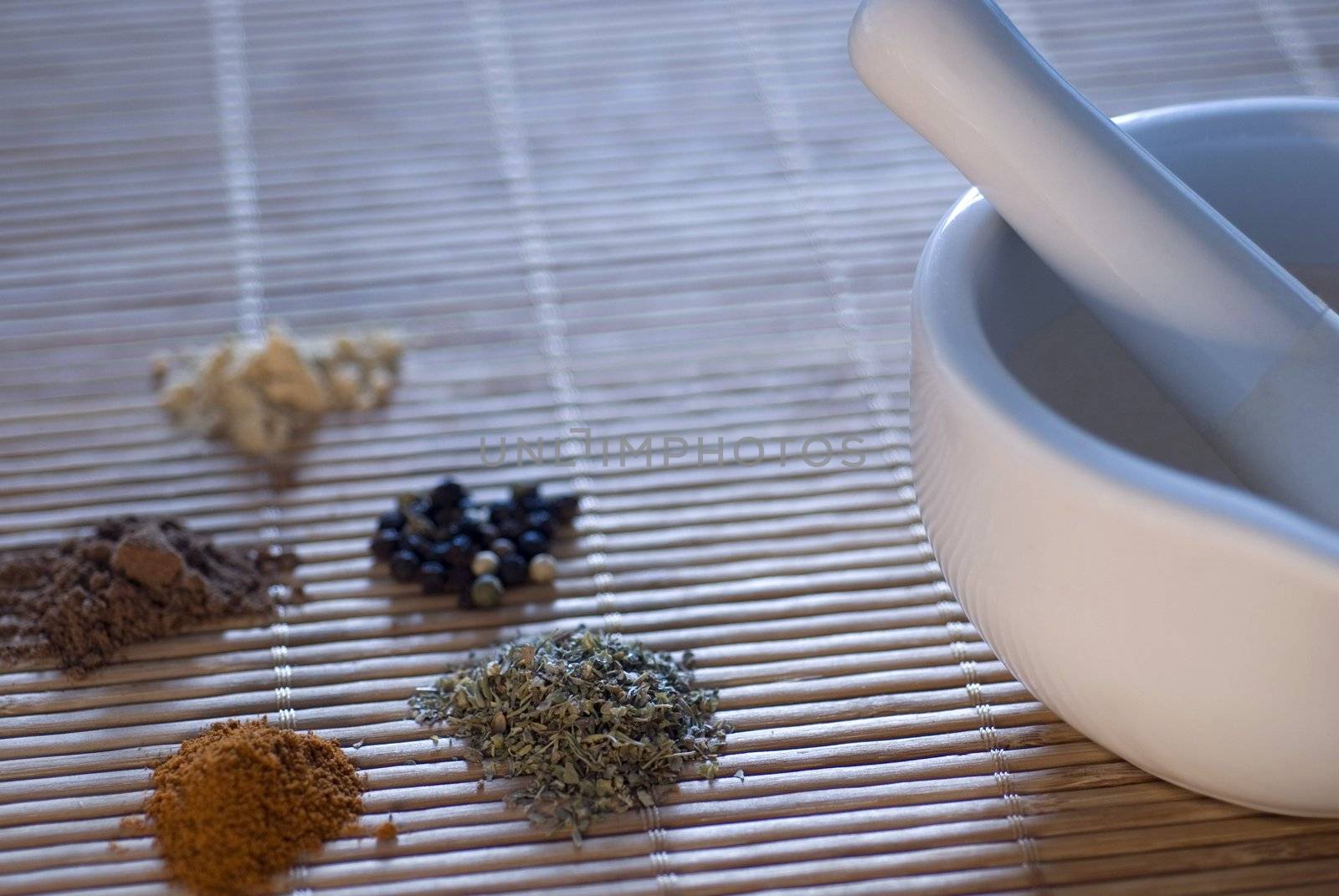 a pestle and mortar with a selection of ground spices, coriander, chilli, pepper, and cumin - narrow depth of field