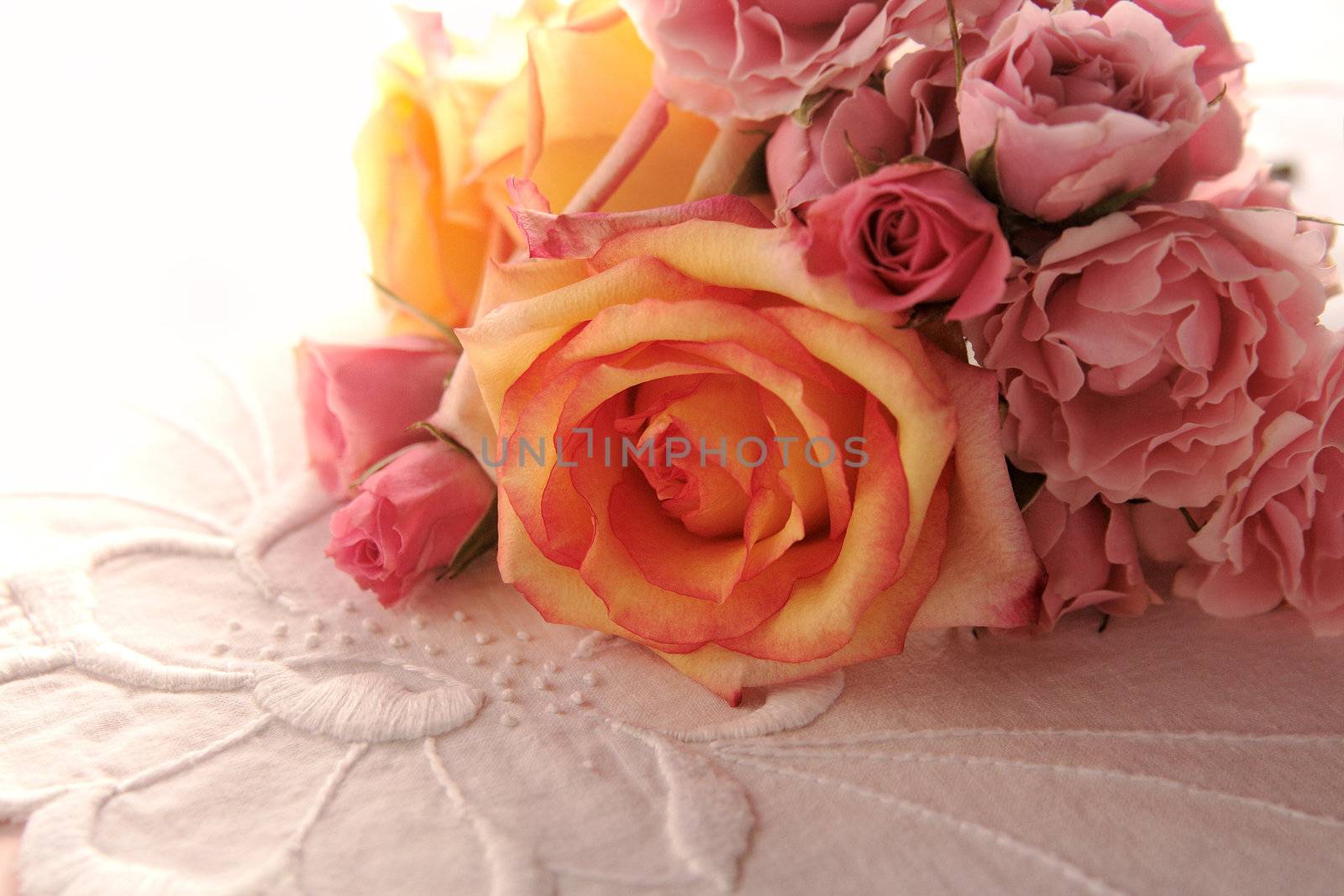 pink and yellow roses on a decorative white cloth