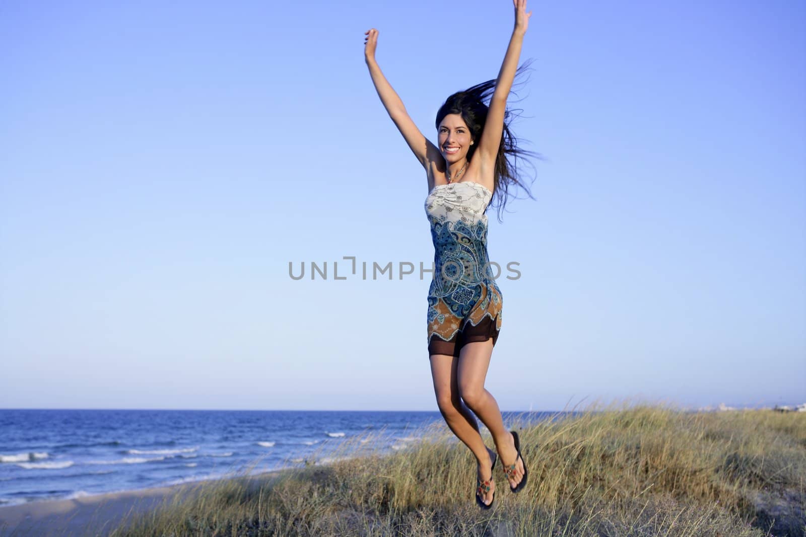 Beautiful brunette jumping in the summer blue beach