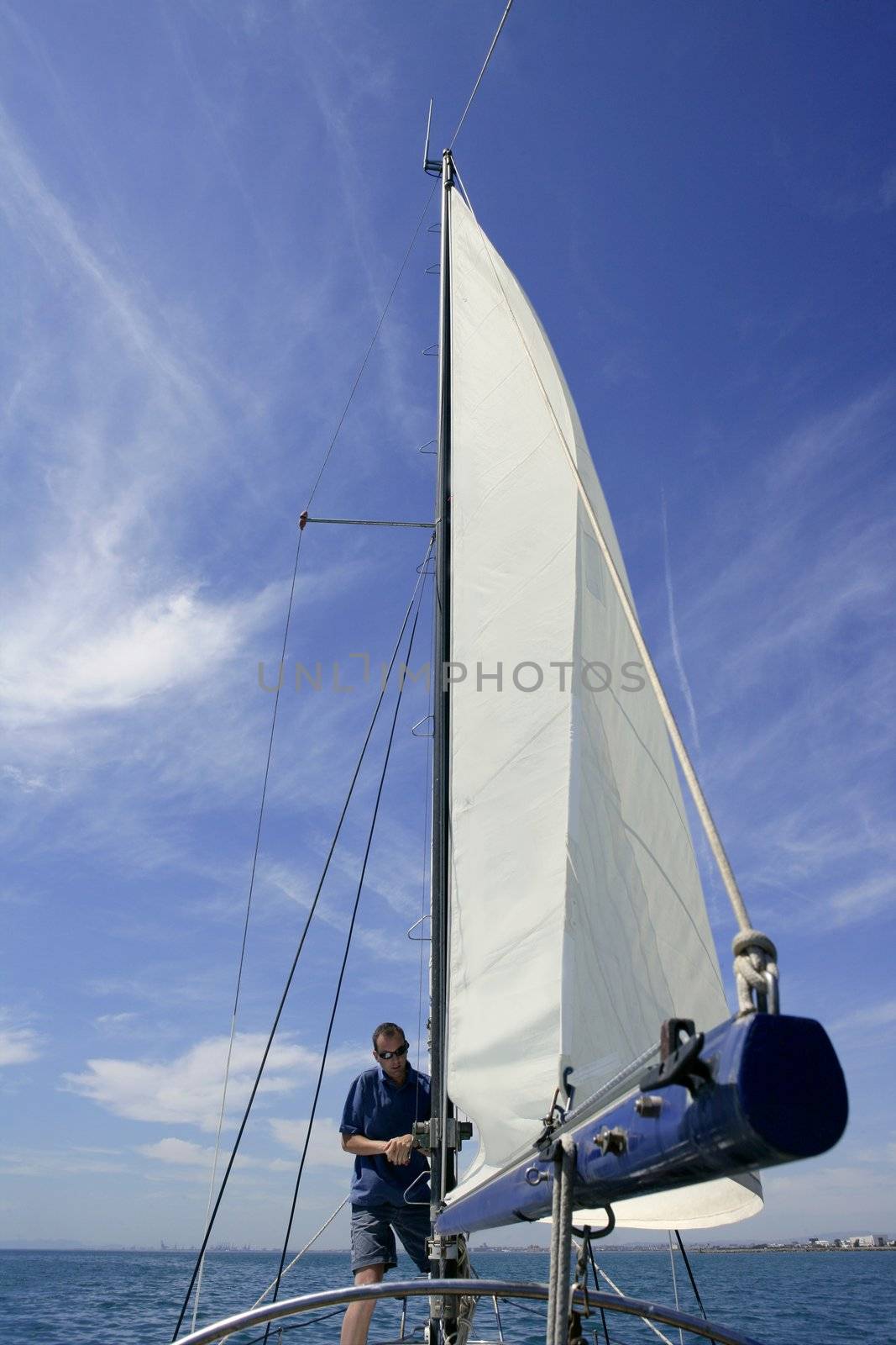 Sailor in sailboat rigging the sails by lunamarina