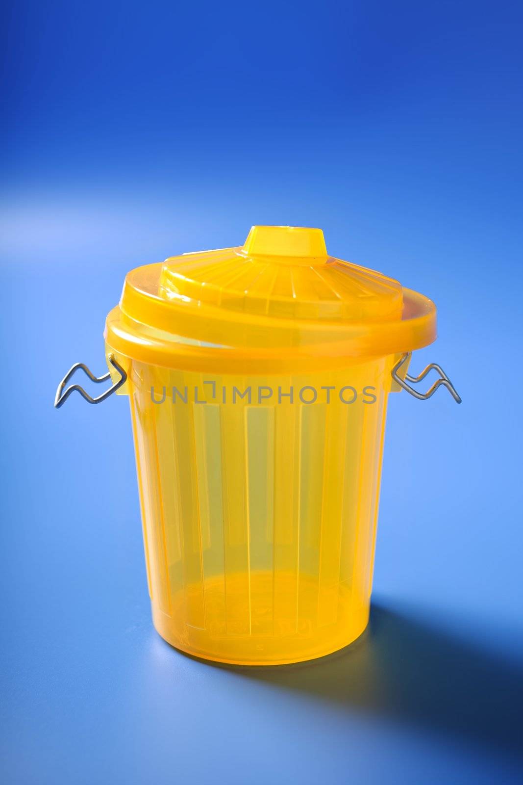 Yellow trash dustbin over blue background with shadows