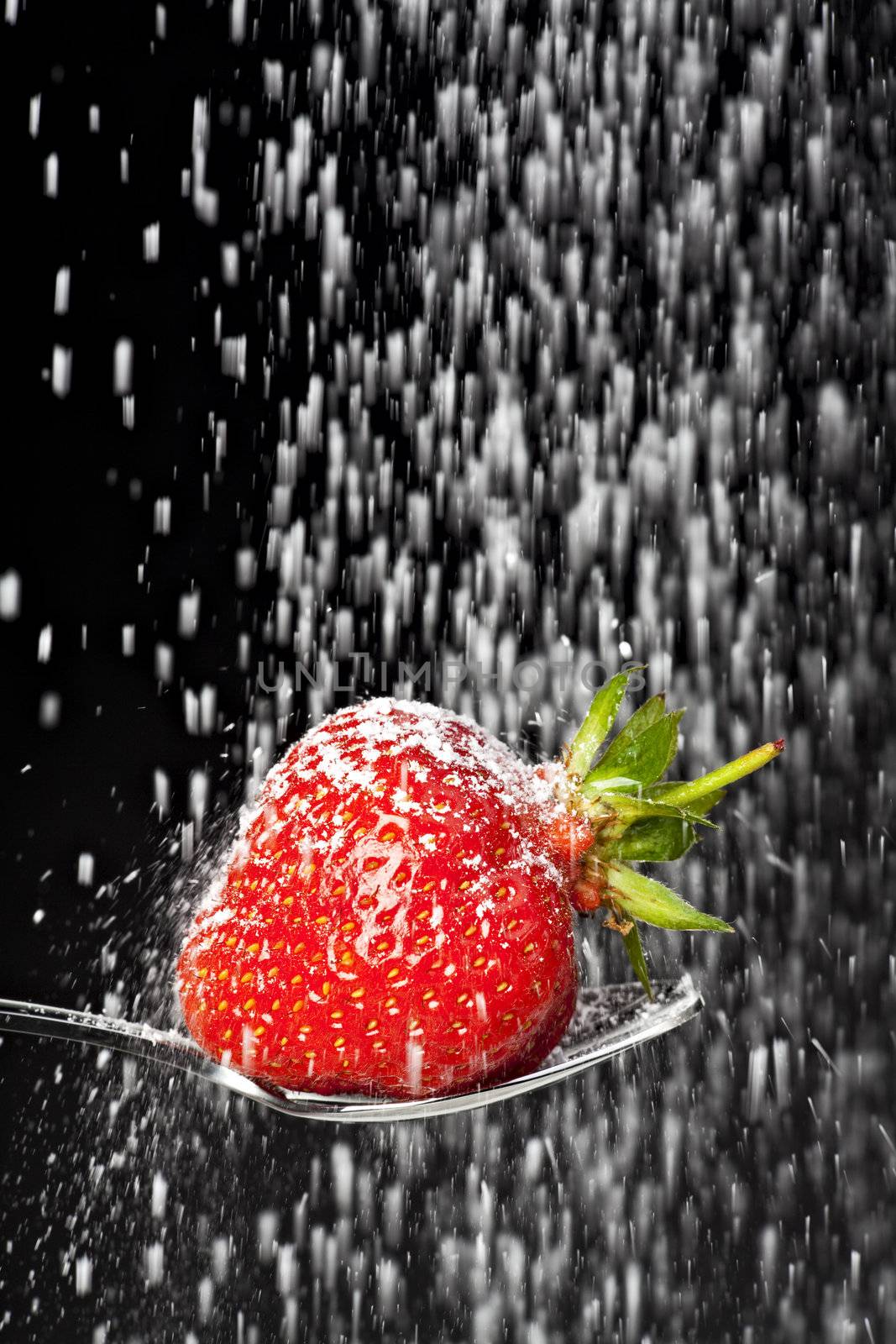 icing sugar falling on a strawberry on a spoon