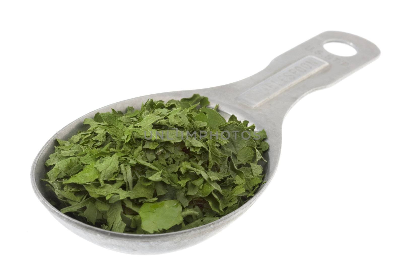 dried parsley weeds on aluminum measuring tablespoon isolated on white