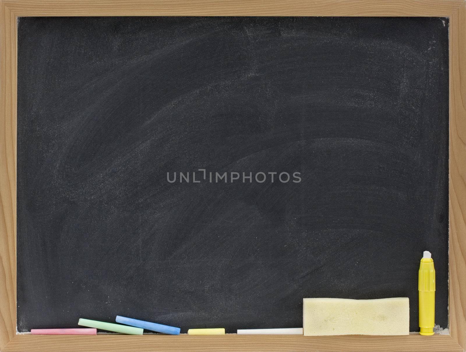 small blank blackboard in wooden frame with pieces of chalk and eraser sponge