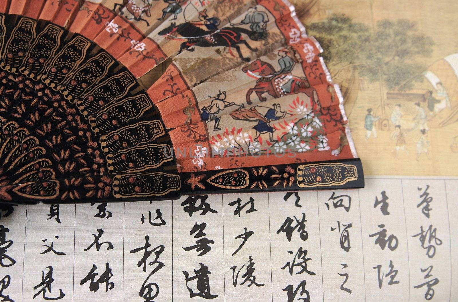 decorative but damaged old hand fan over an art paper background of Chinese calligraphy and figures