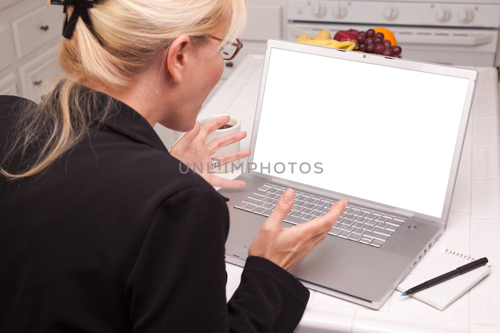 Excited Woman In Kitchen Using Laptop with Blank Screen by Feverpitched