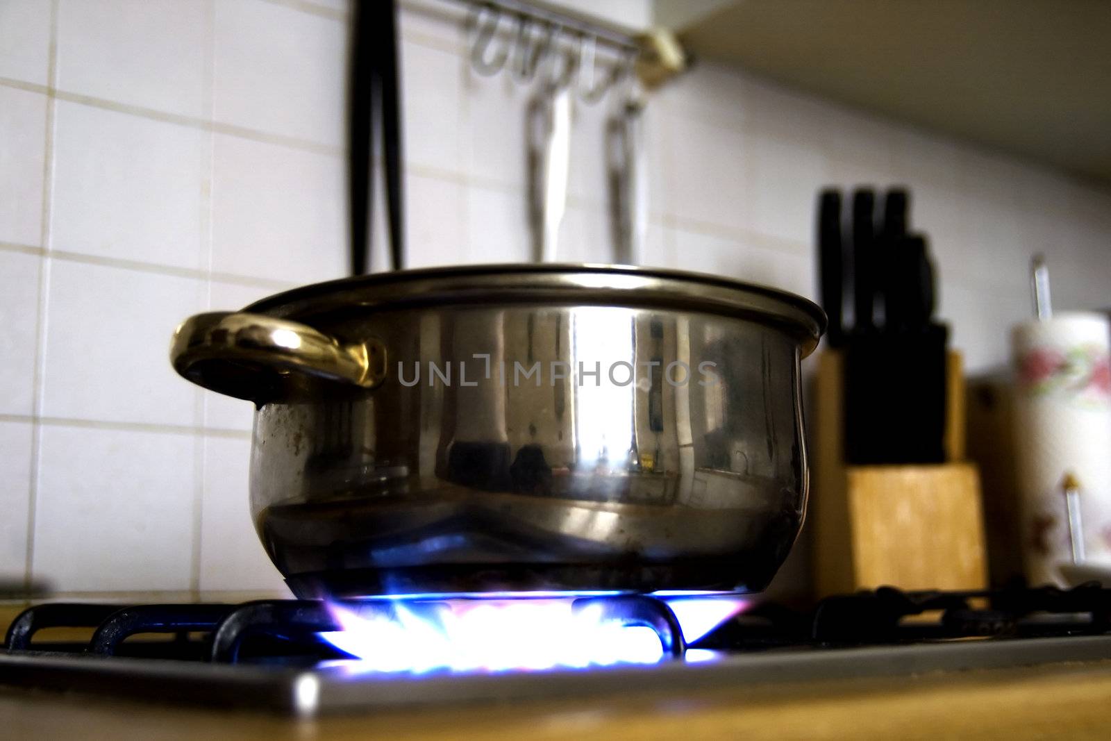 A Pot in a kitchen, fire lit, tools on the background