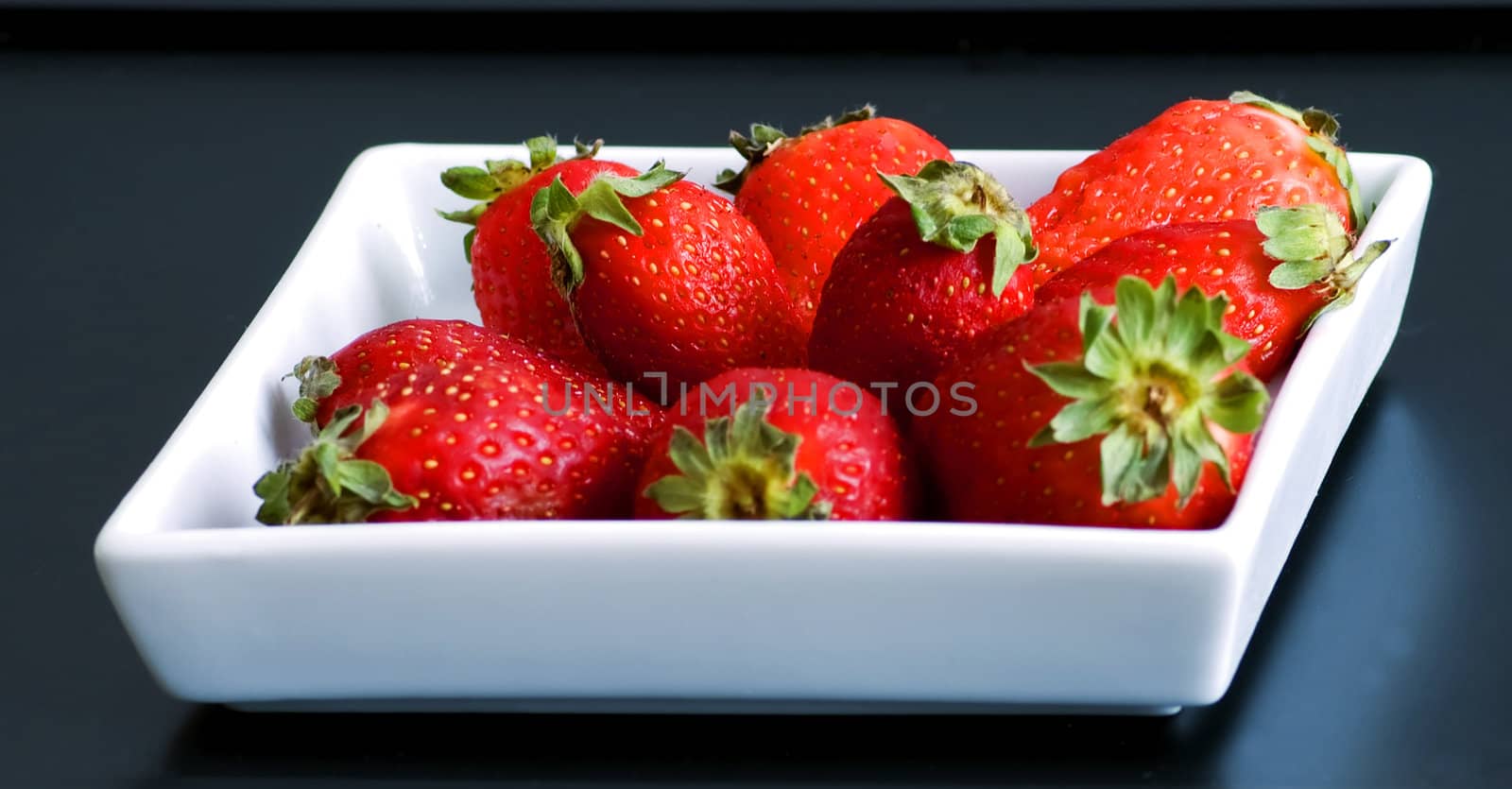 White plate full of red and mature strawberries