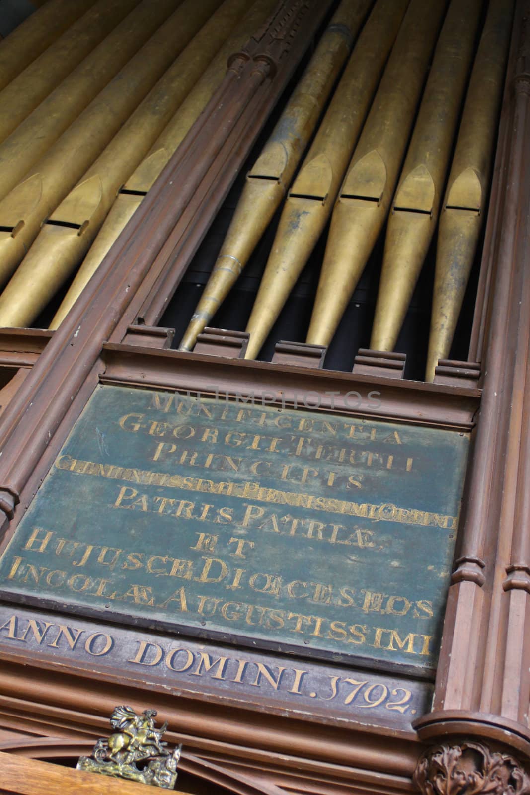 Angled view of brass church organ pipes, with a hand scribed panel in Latin with the dateAnno Domini 1792. located in St.Thoma's Church in Salisbury, Wiltshire.