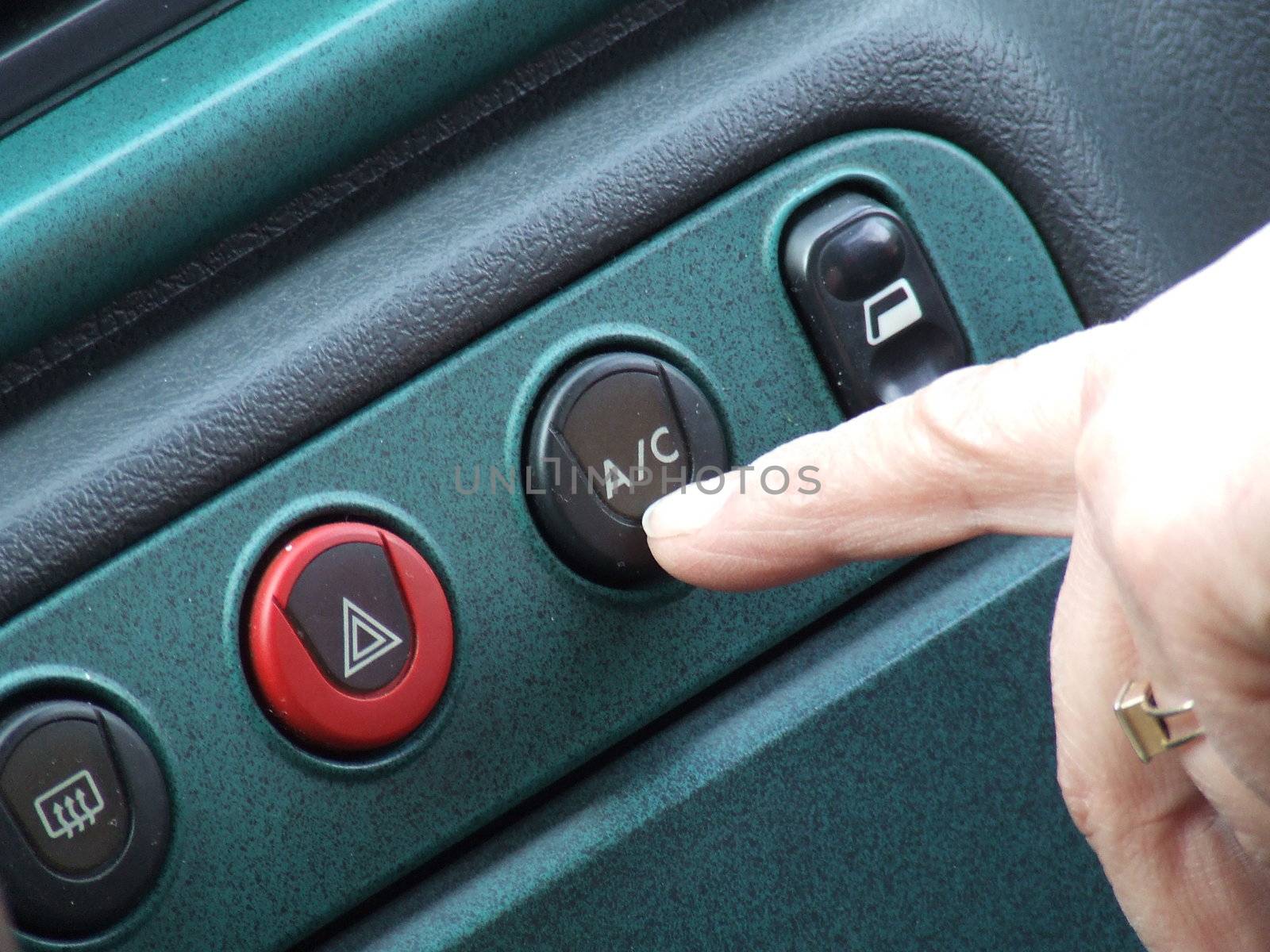 Pressing the index finger on the button on the air conditioner in the car
