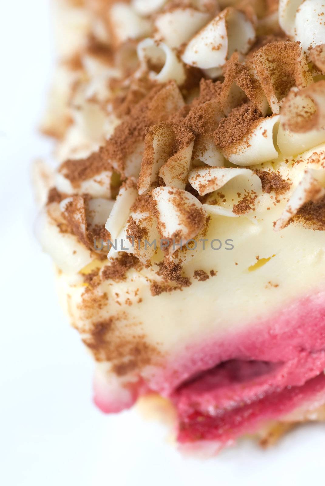A slice of raspberry cheesecake with white chocolate shavings and chocolate dust toppings