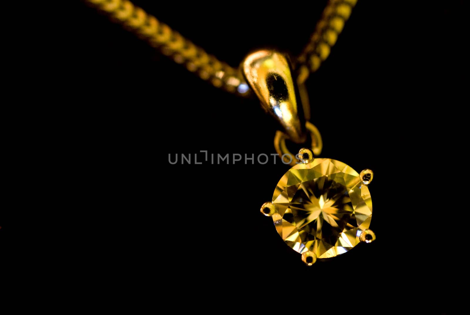 Still life of a diamond pendant on a necklace on a black surface
