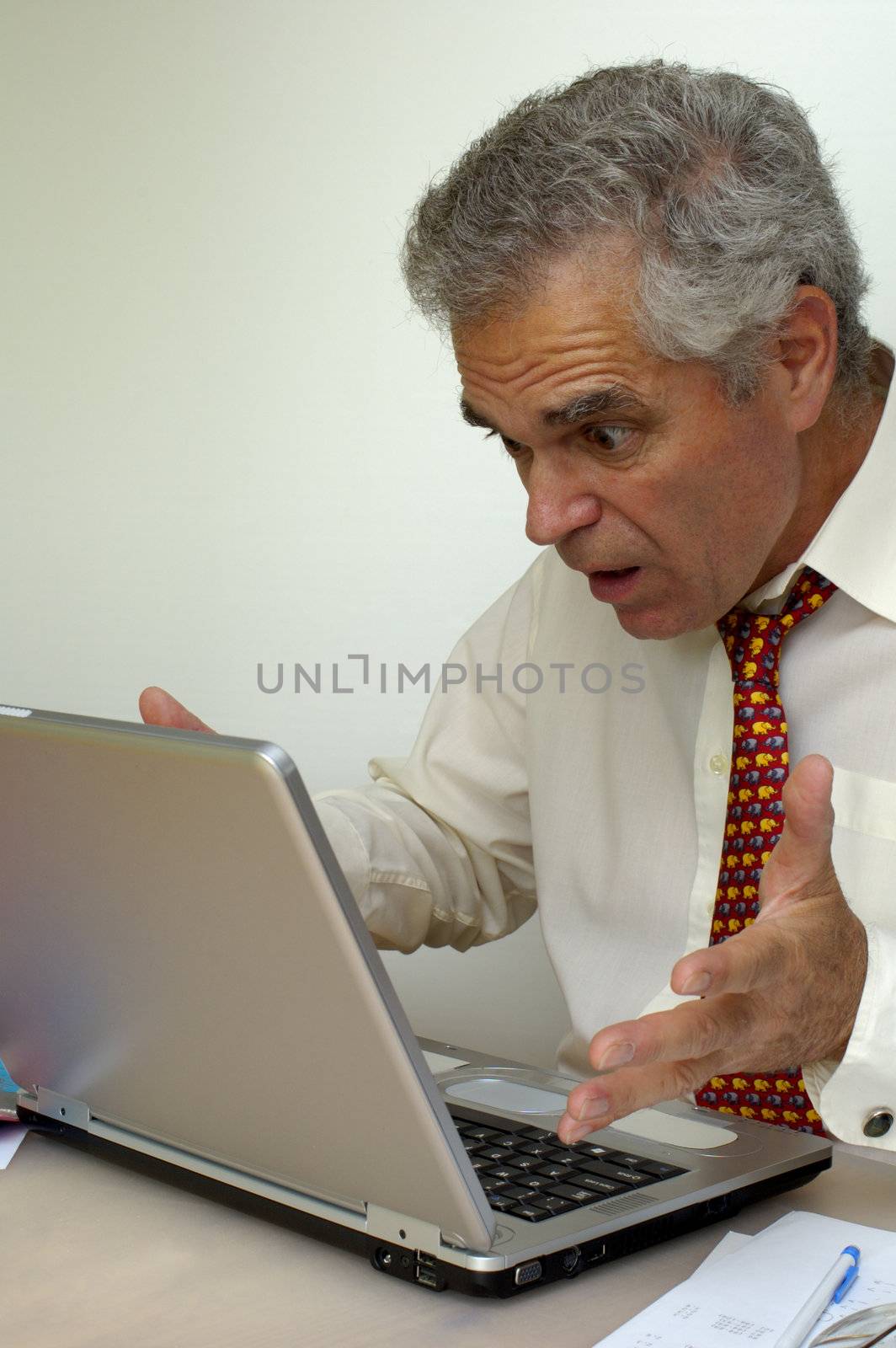 A businessman looks at the screen of his laptop and holds out his hands in amazement. What's the pesky machine up to now?