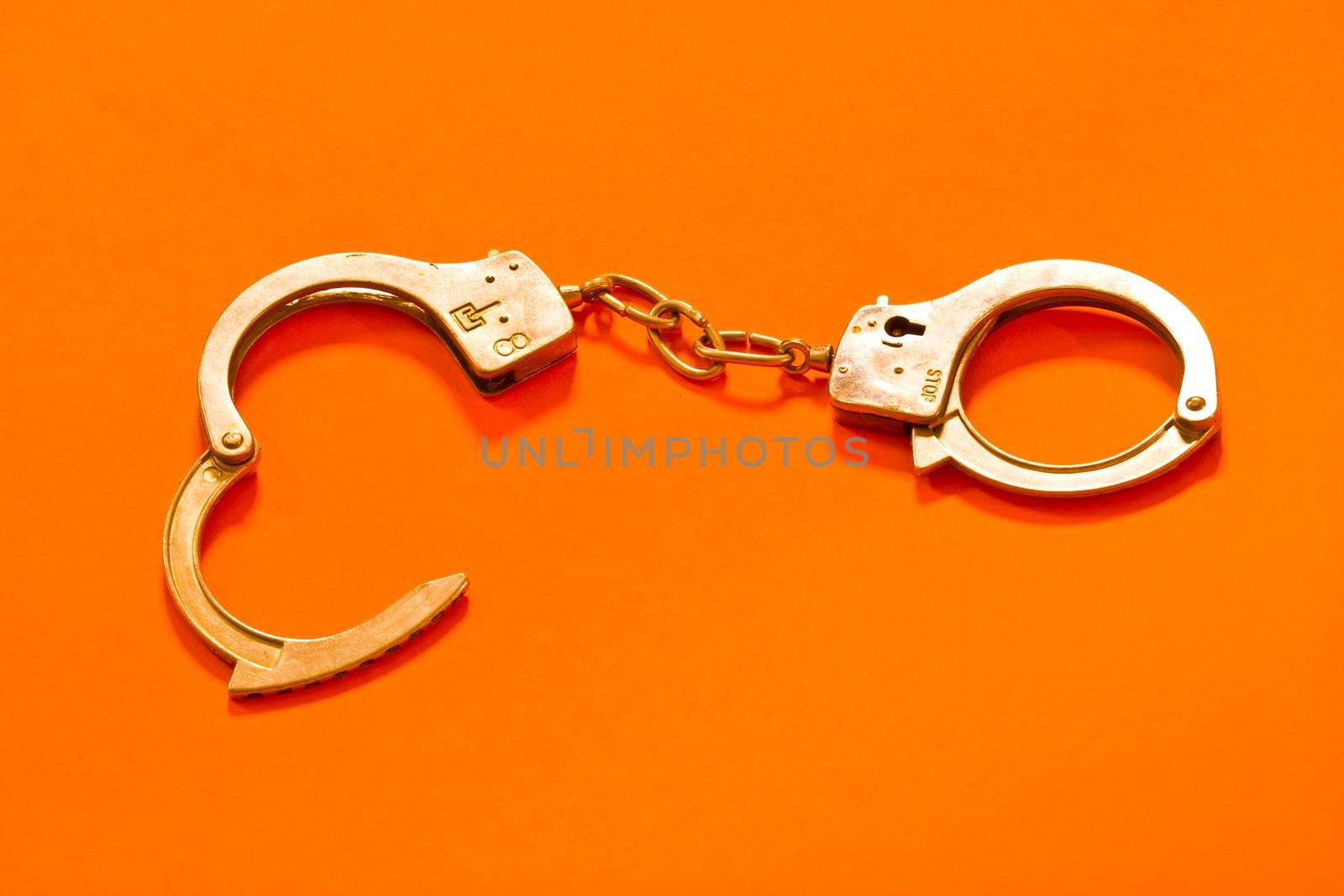 Open metal handcuffs on the orange background