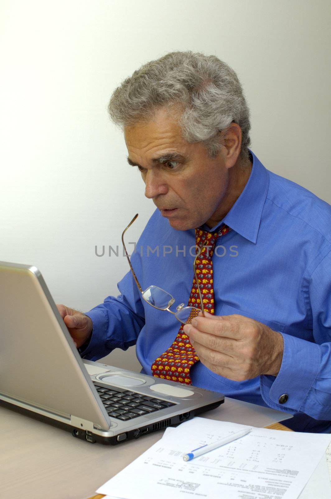 A businessman looks at his laptop computer as though it's about to explode. Something has gone seriously wrong.