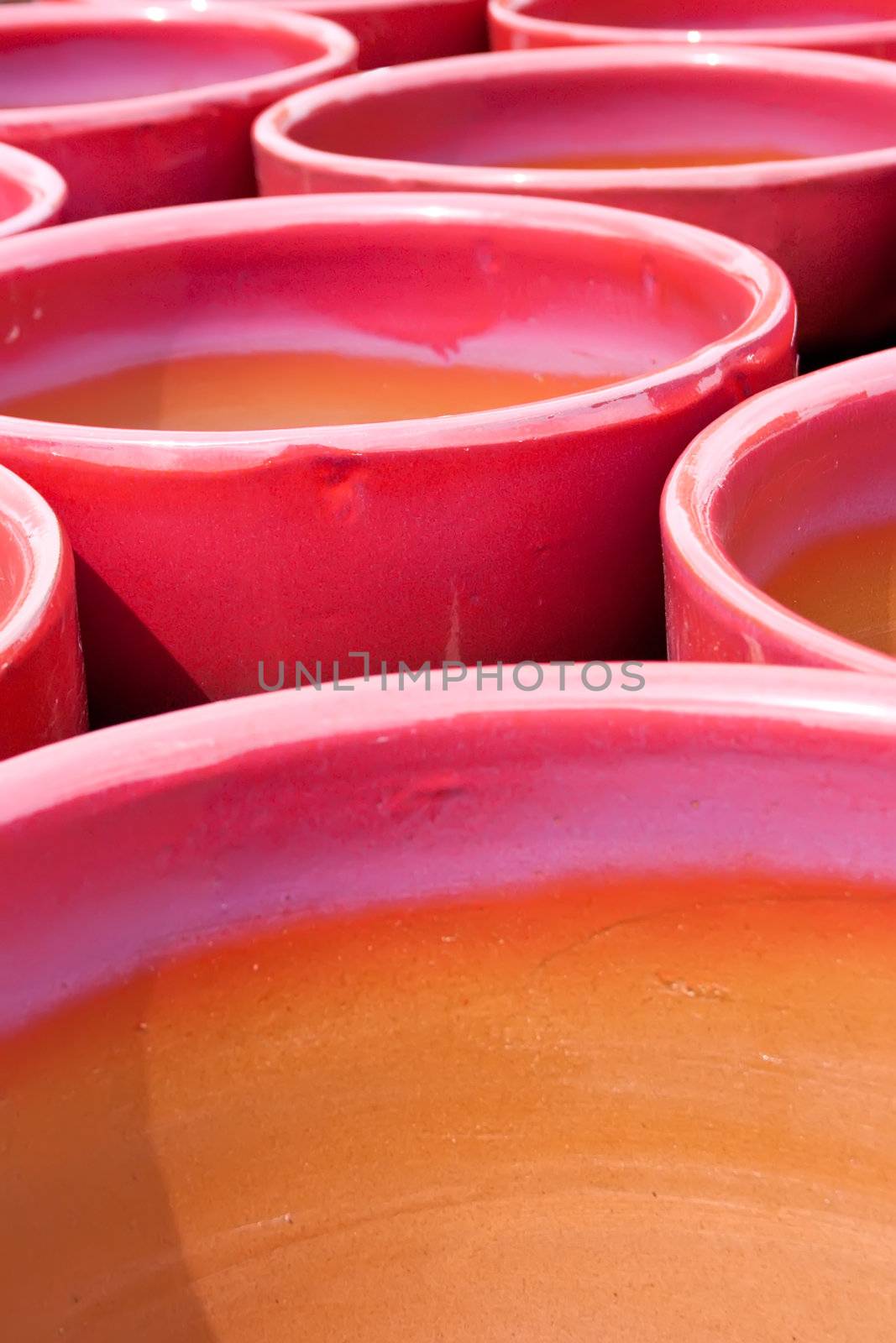 a collection of bright red and purple glazed flower pots