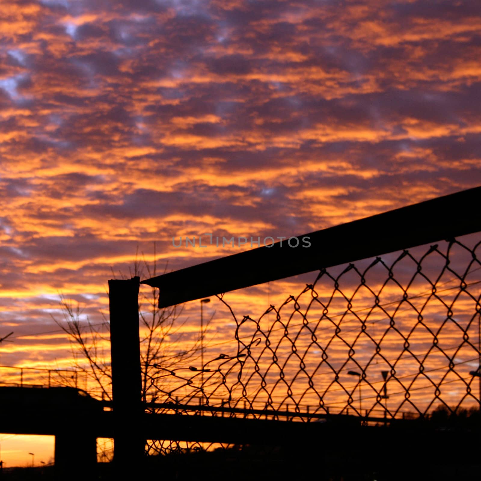 Silhouette of a broken fence against the sky filled with beautifully coloured clouds