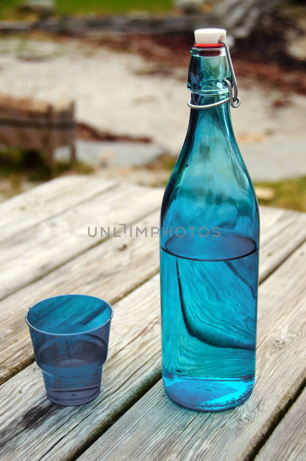 A blue bottle with water on a picnic table