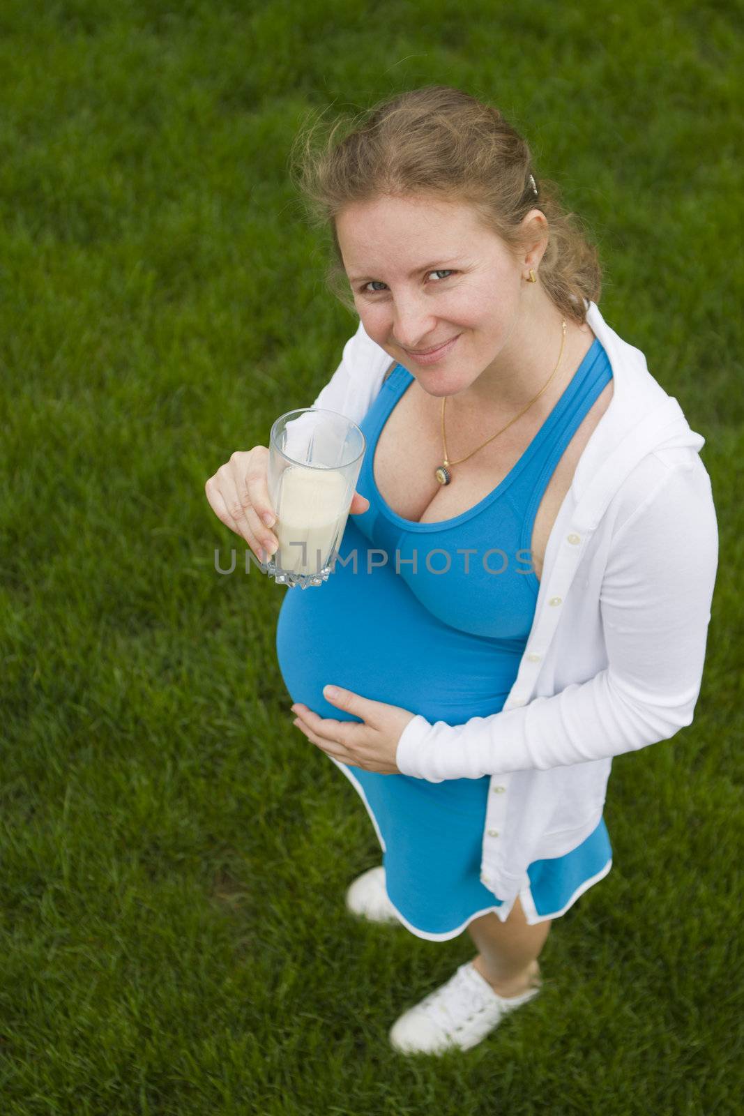 A helathy woman posing with a glass of milk in her blue outfit.