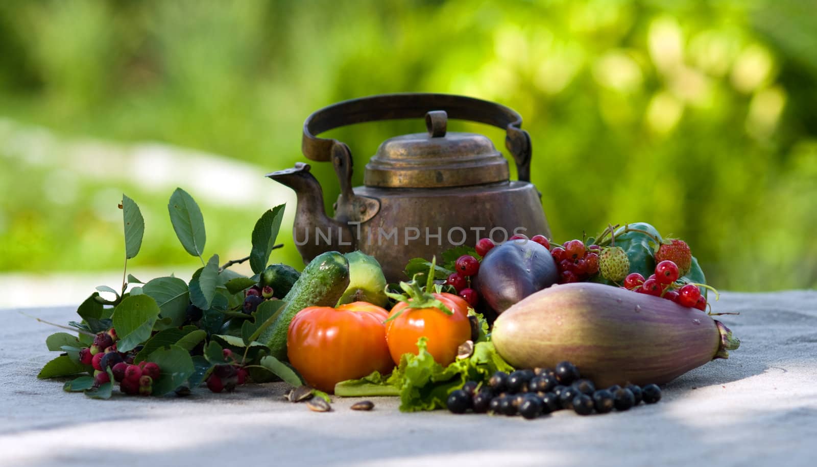 Berries, vegetables and an ancient teapot on a grey cloth