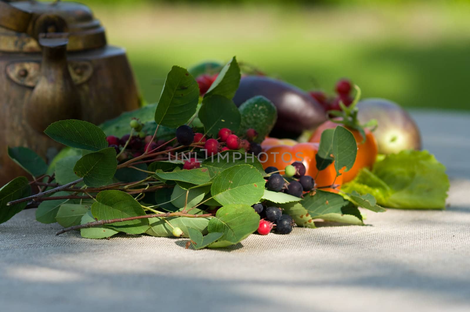 Berries, vegetables and an ancient teapot on a grey cloth