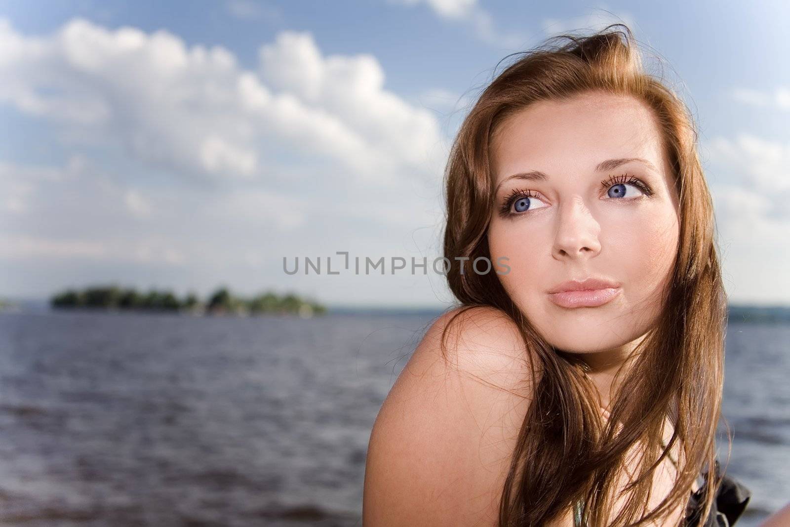 Pretty woman in sunlight near the water
