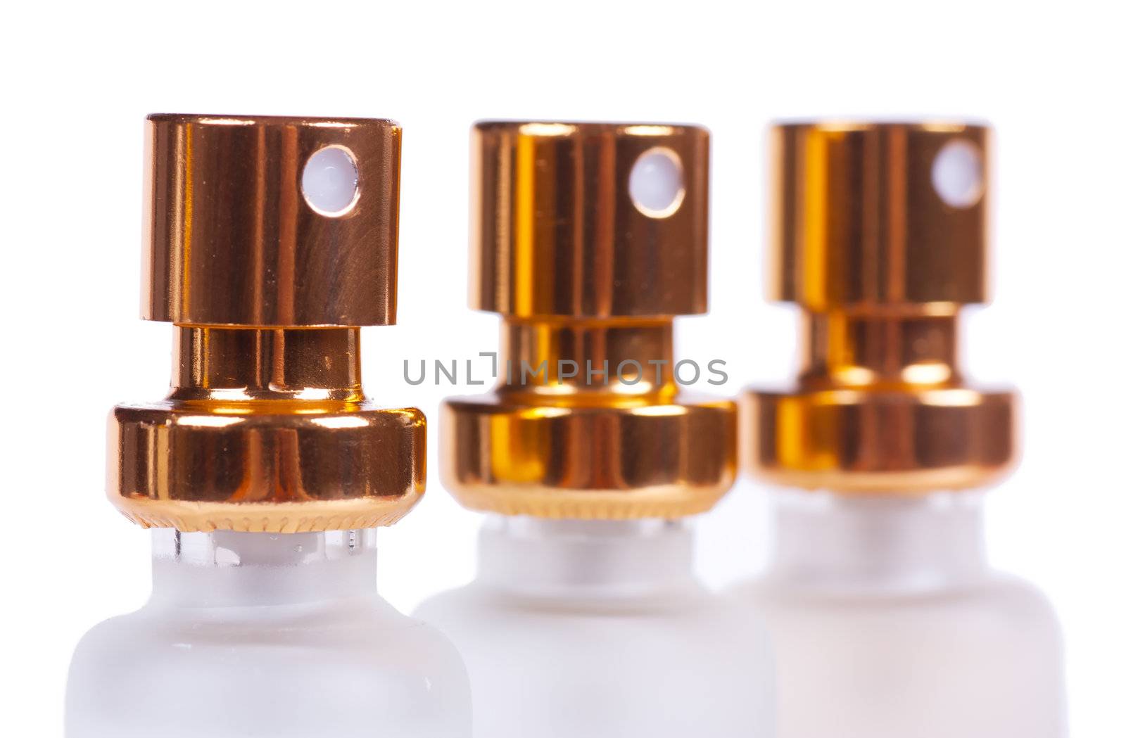 Sprayers of three perfume bottles isolated over white background. Macro view.