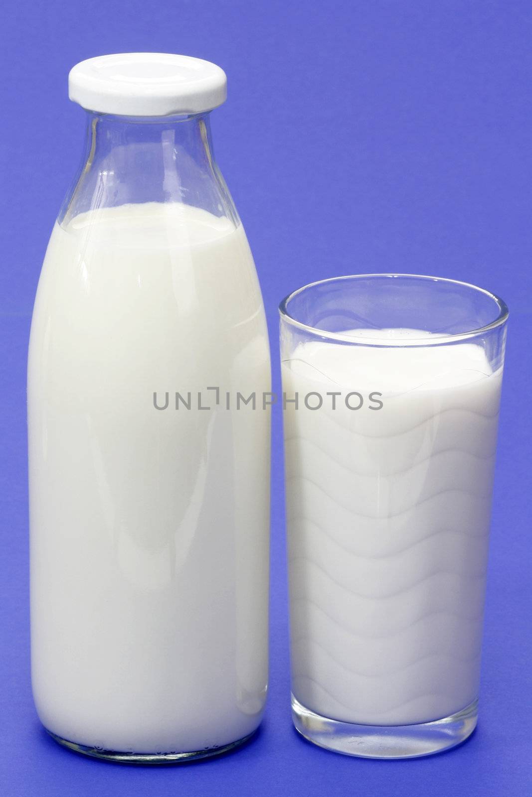 Glass of milk and milkbottle over blue background