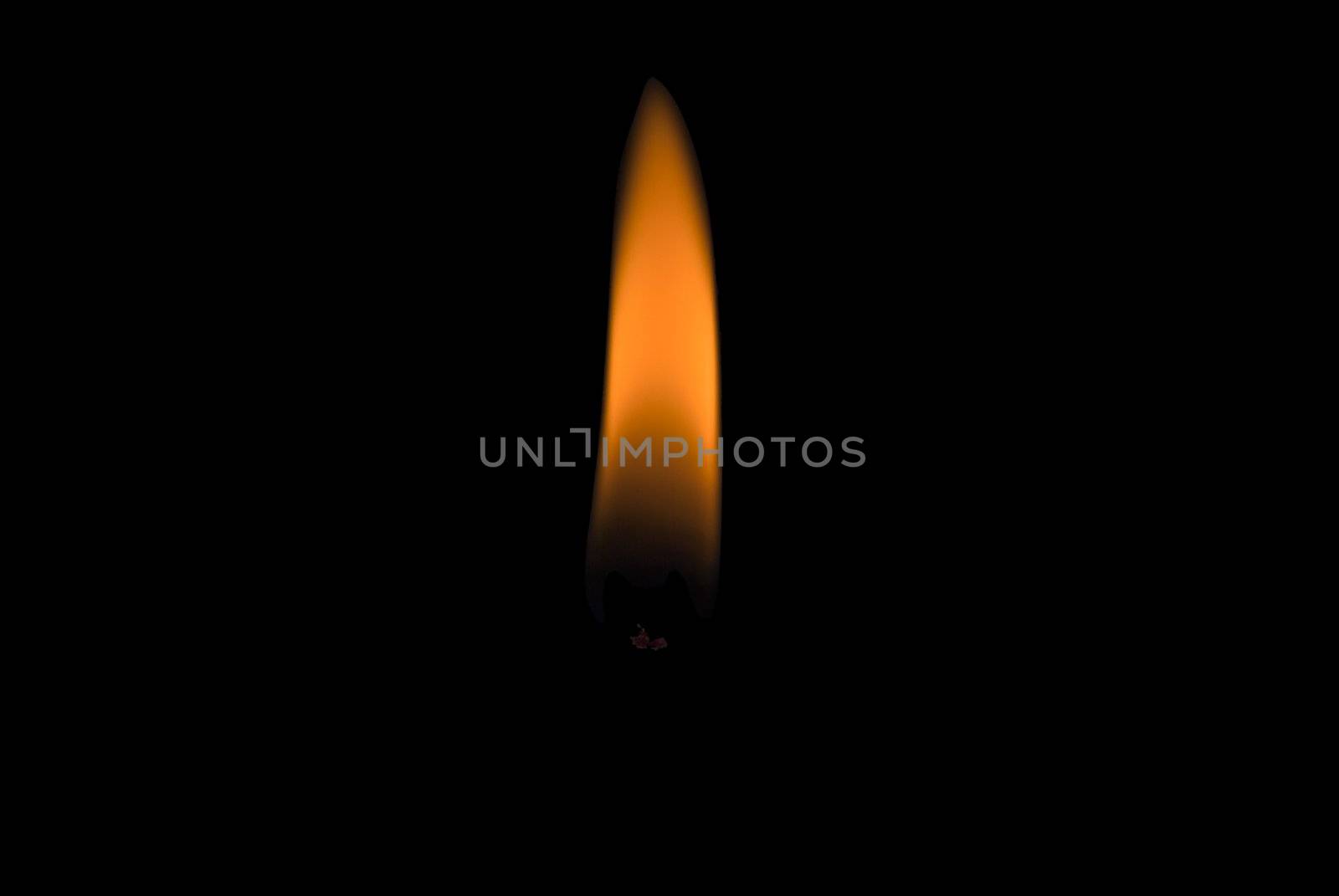 A single candle flame against a black background.  Tip of glowing wick visible.