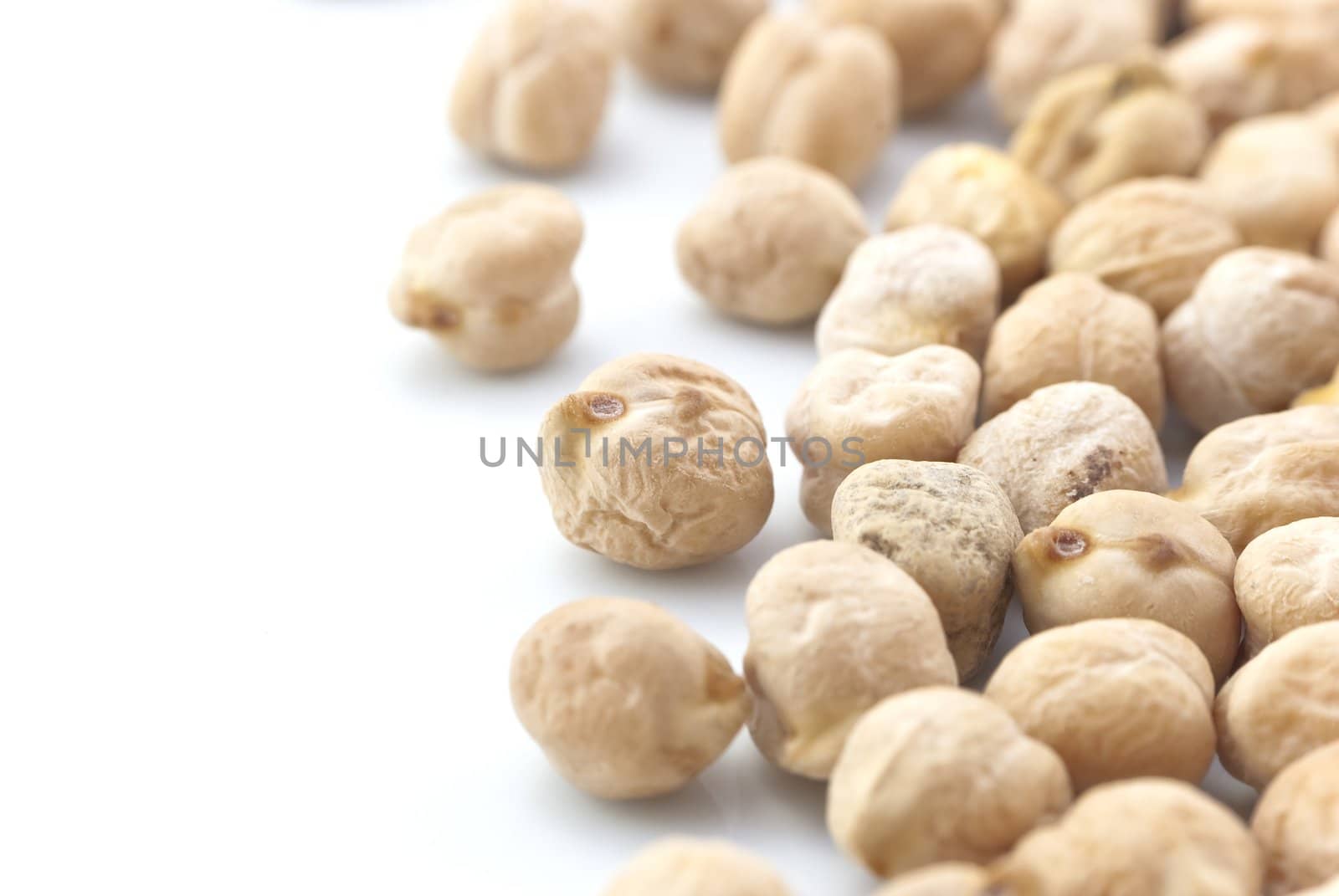 Close-up (macro) of raw chickpeas (garbanzo beans) emerging from right side of frame.  White copy space to the left.