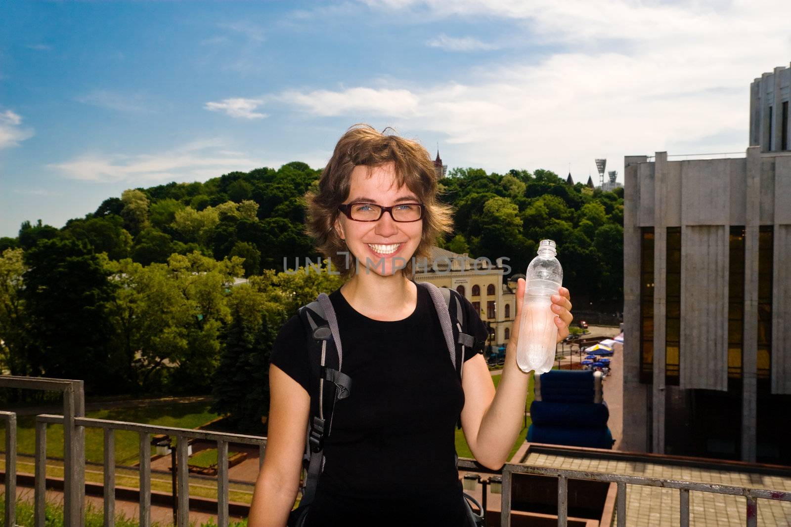 Young woman walking in the city and refreshing herself with cold fresh water