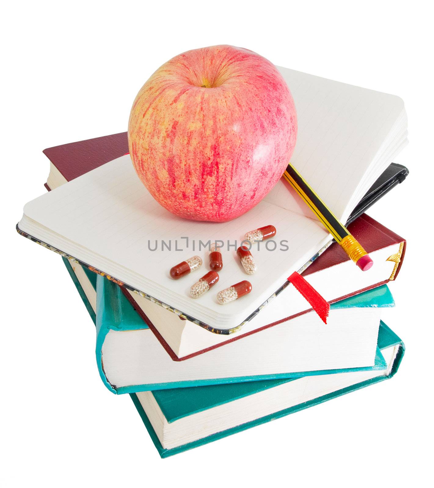 Apple with pills and pencil on textbook heap as ways to stimulate memory