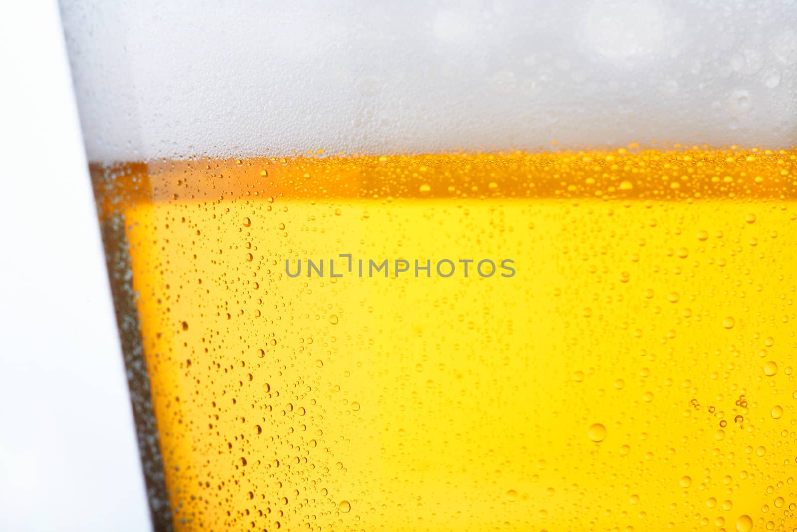 Fresh glass of pils beer with froth and condensed water pearls