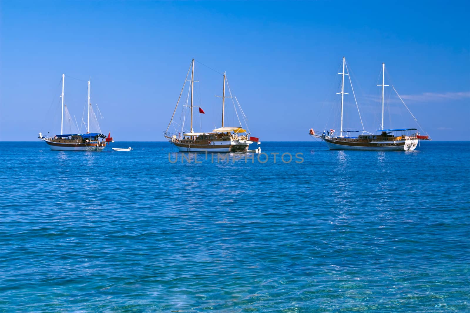 Three sailboats with lowered sails in sunny weather, with copyspace