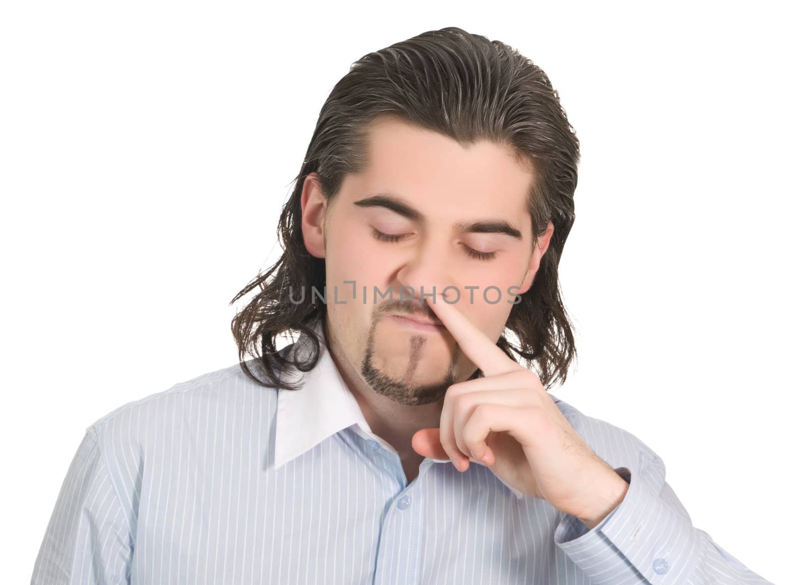 Young funny dark haired guy in light blue shirt picks his nose isolated on white