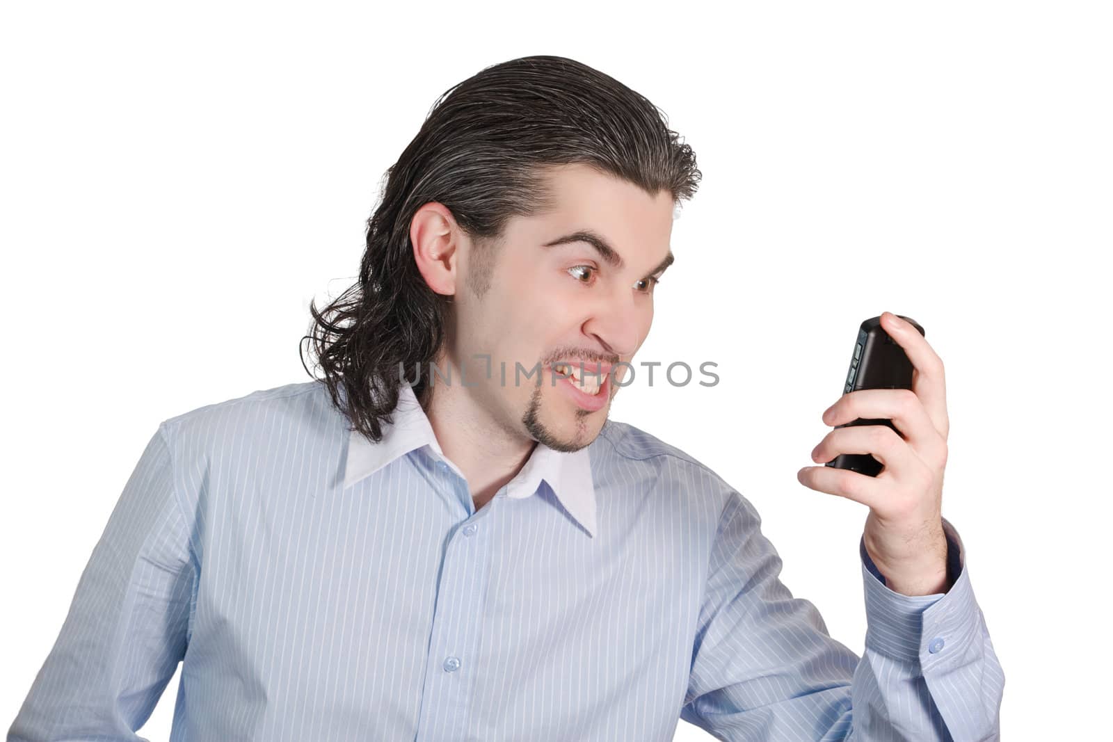 Young dark haired caucasian man in light blue striped shirt looking angrily at his mobile phone isolated on white