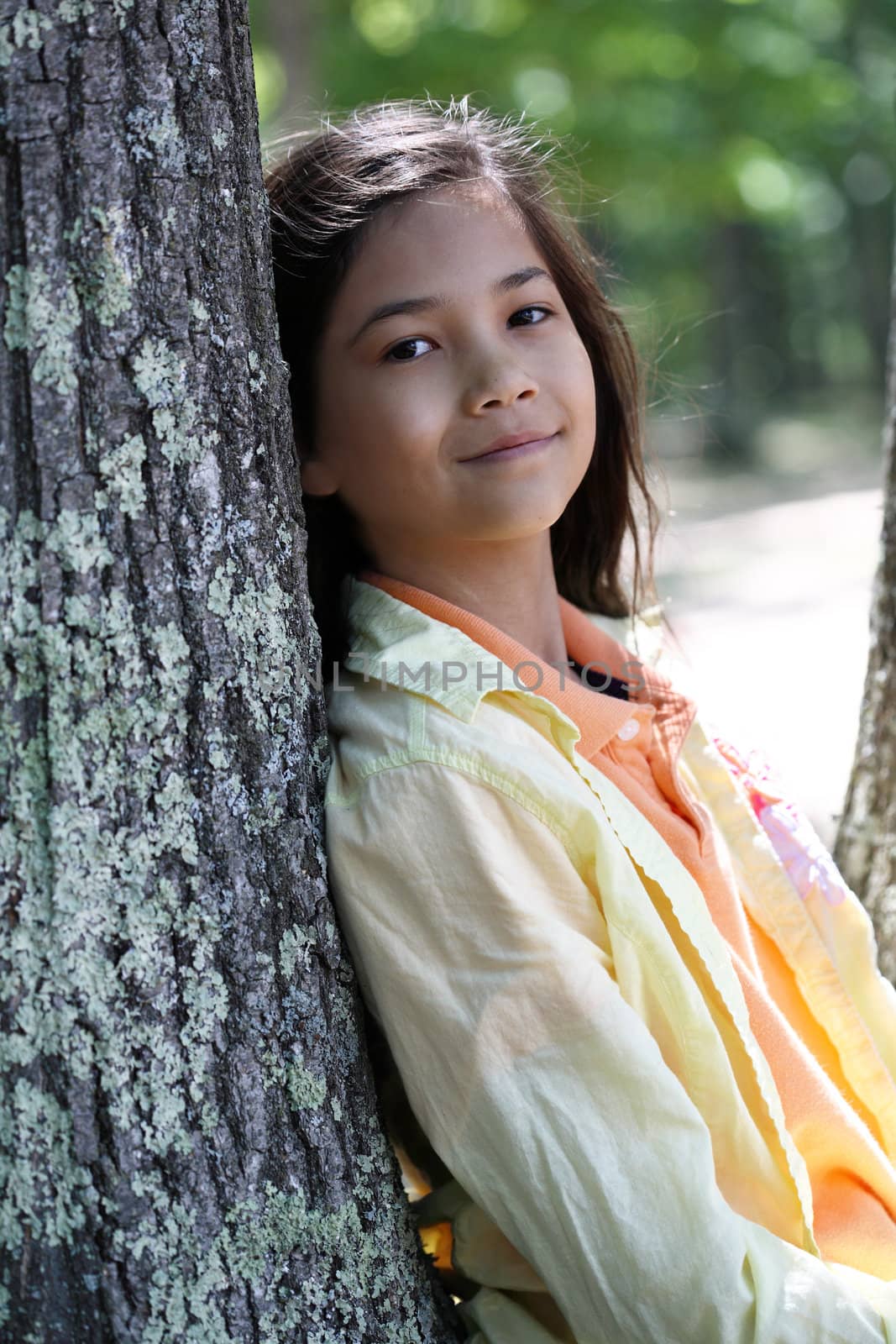 Young girl relaxing against tree in summer. Part Thai - Scandinavian descent