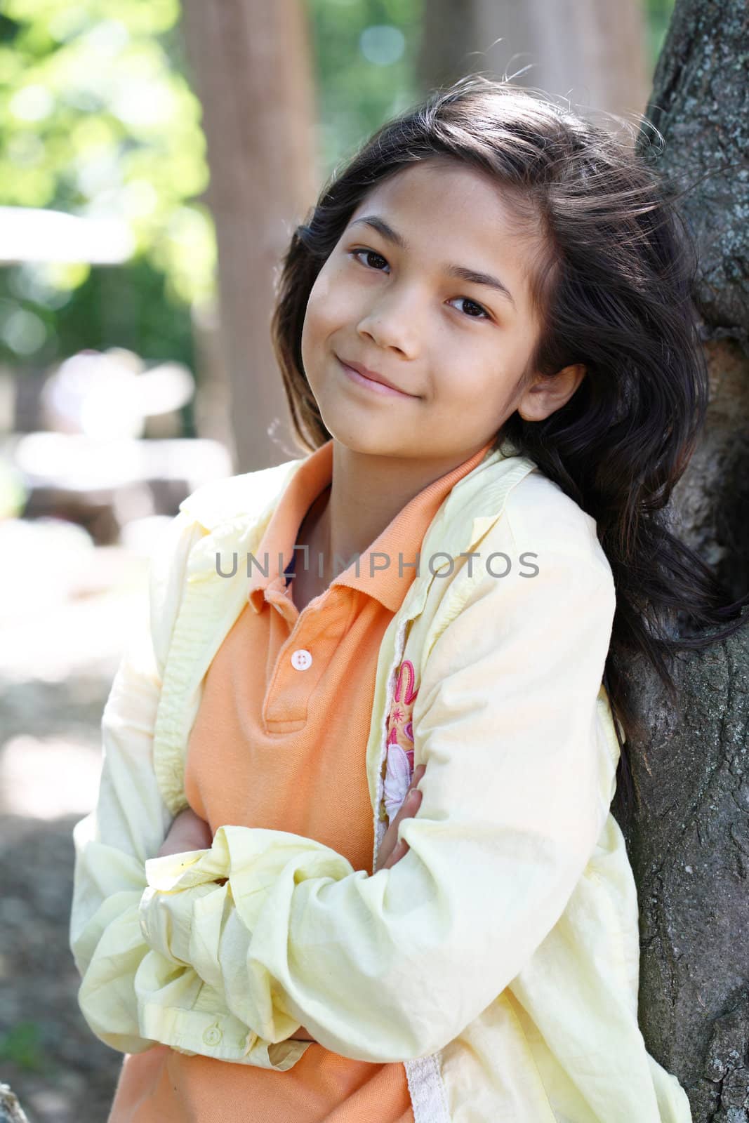 Young girl relaxing against tree in summer. Part Thai - Scandinavian descent