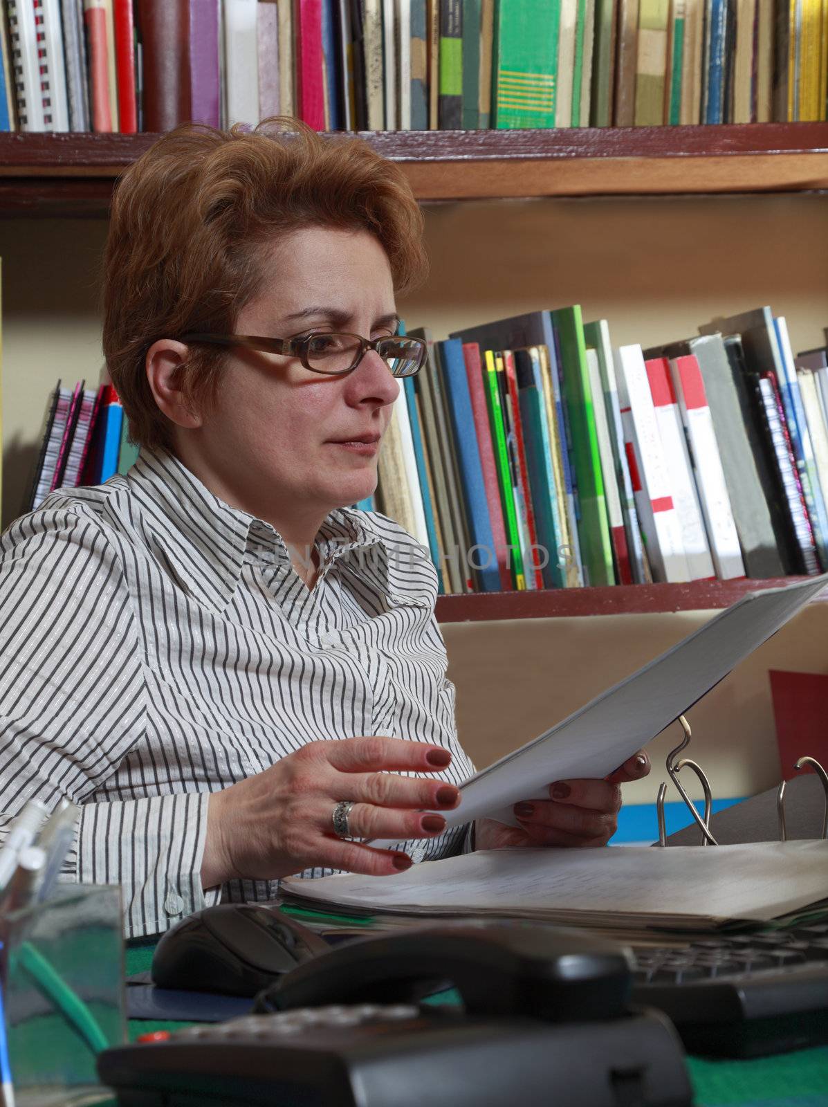 Woman with a folder at her home business desk.