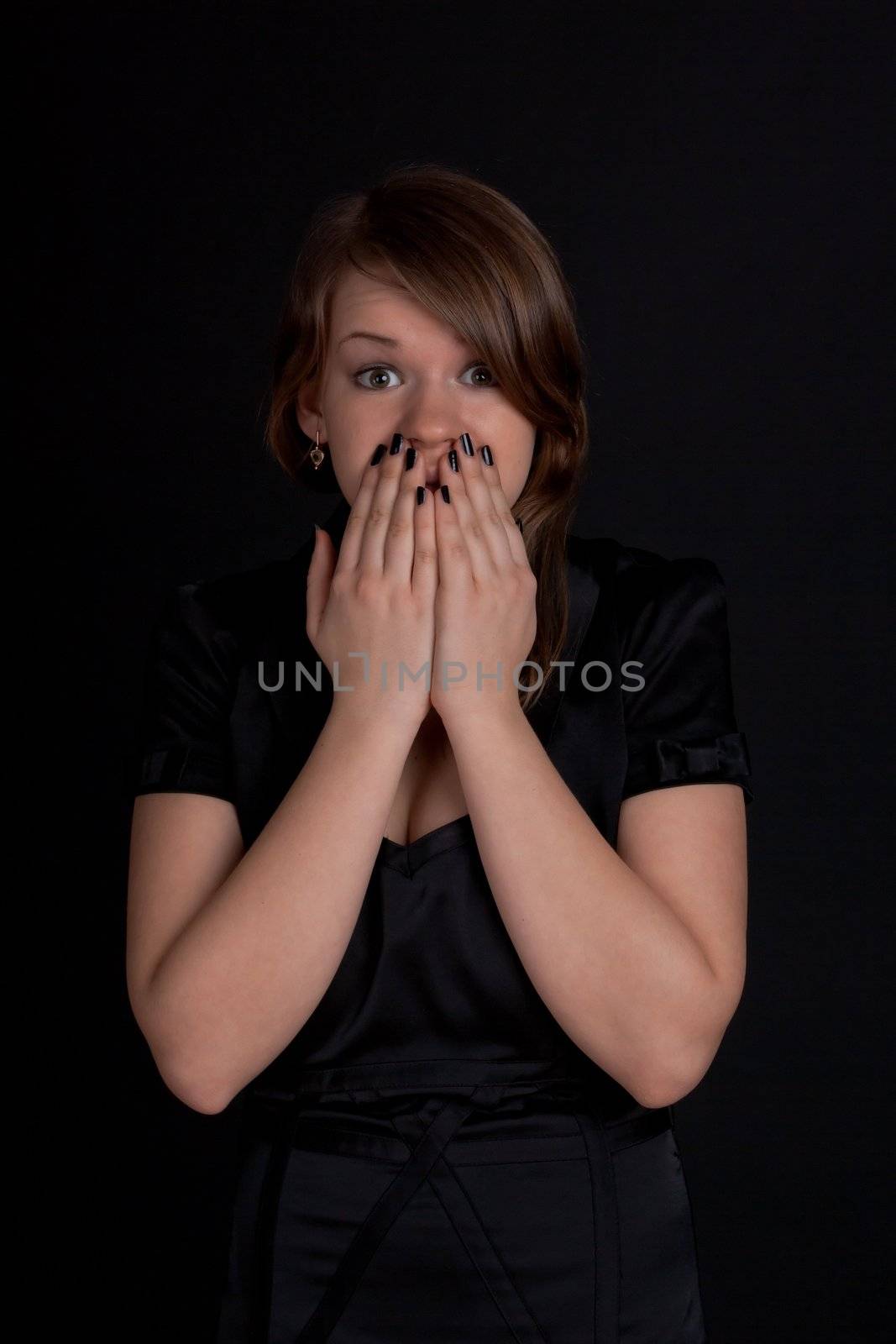 Frightened young girl closes her mouth her hands